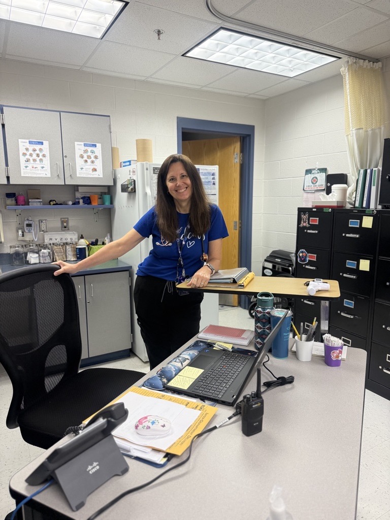 nurse standing at desk in clinic smiling