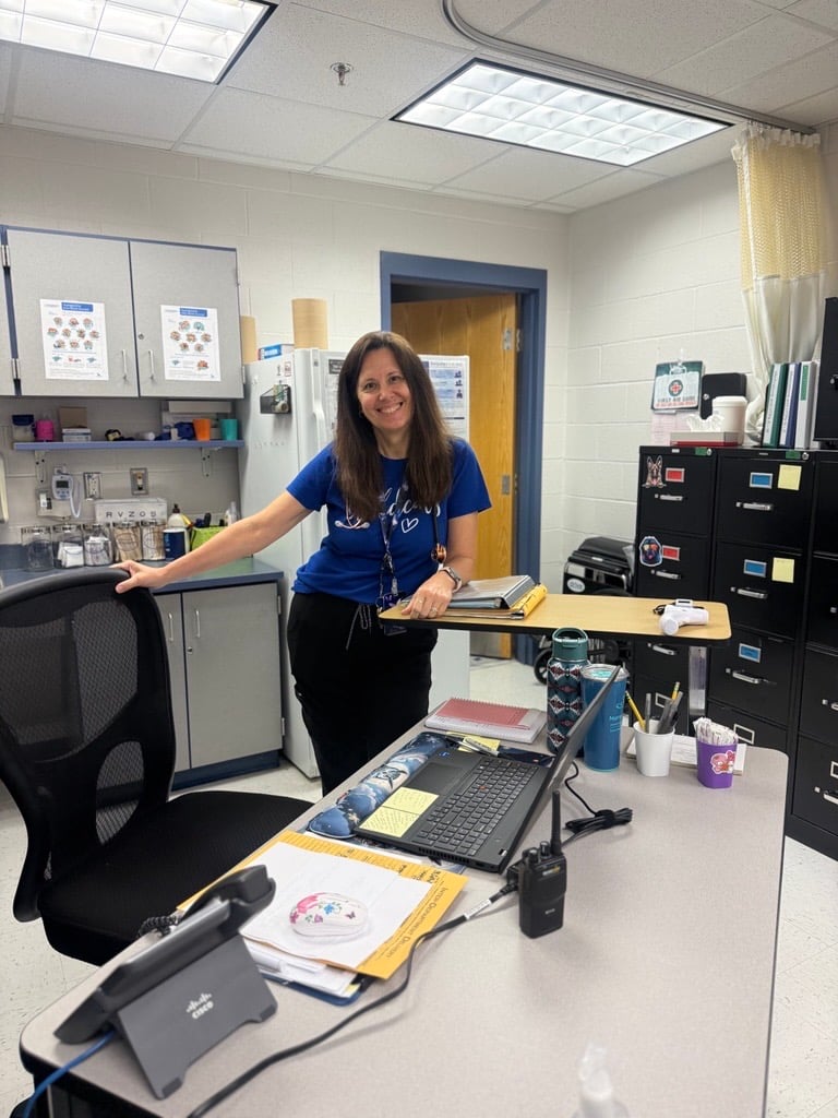 nurse standing at desk in clinic smiling